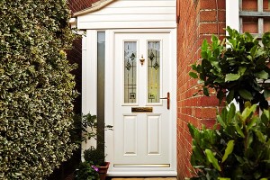 White front door framed by brick wall and hedge