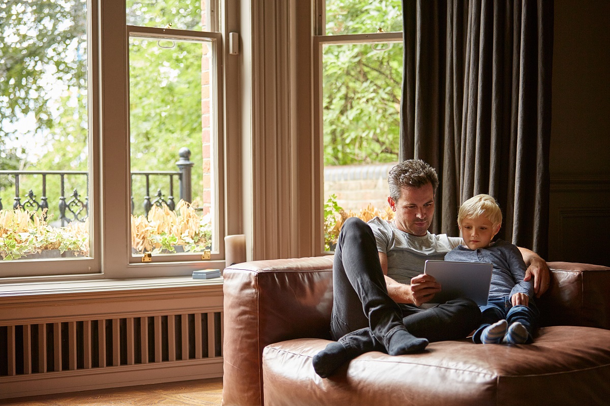 Shot of a father and his young son sitting together on the living room sofa using a digital tablet